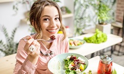 Woman smiling while eating healthy meal in kitchen