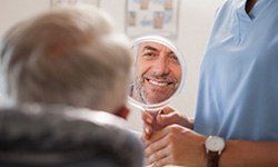 Man smiling at reflection in handheld mirror