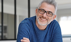 Man in blue shirt smiling with arms folded