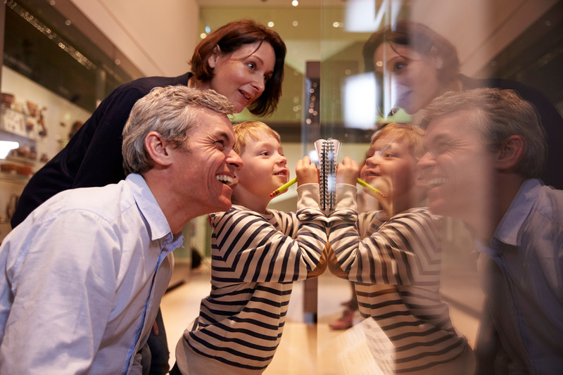 Patient smiling with family at the museum after getting cosmetic dentistry